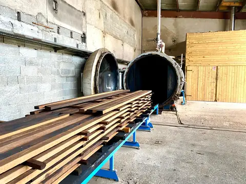 Autoclave de traitement ouvert à côté de bois débité sur un chariot
