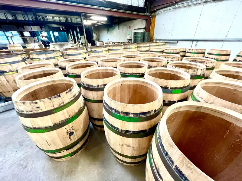 Nombreux fûts en bois alignés dans un atelier de tonnellerie