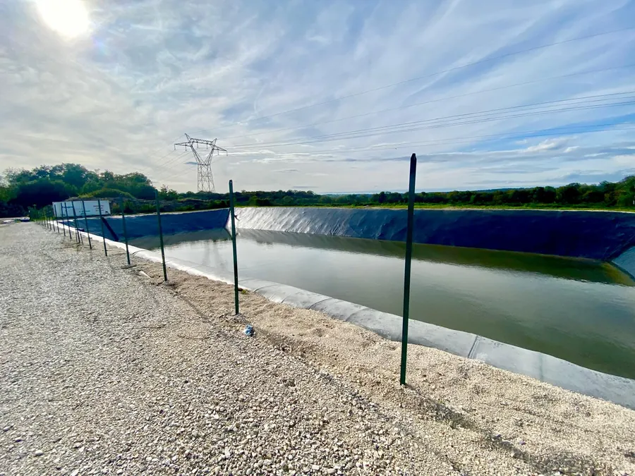 Bassin aménagé en bordure d’un site industriel, sous un ciel dégagé